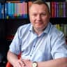 Marek Aleszko na tle regału z książkami